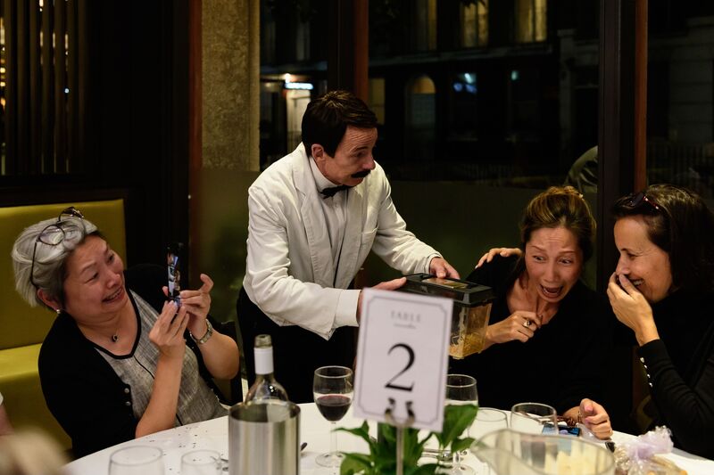 Manuel serving laughing dinner guests