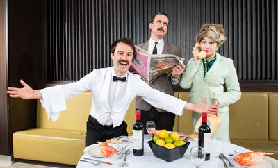 Manuel Basil and Sibyl in front of a set table
